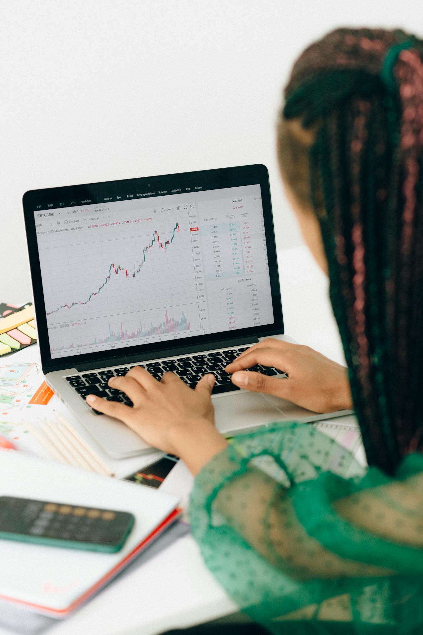 Our Mission A woman working on financial analysis using a laptop with a stock market graph on screen.