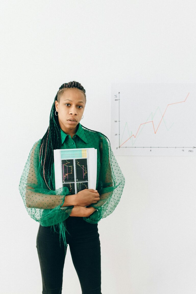 Young businesswoman in green blouse holding financial charts, standing against a growth graph